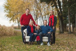 A fall portrait of a family sitting on an antique white couch, Red accents