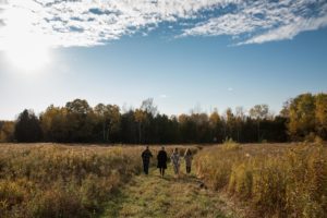 Adult kids walking in a field during the fall with beautiful blue sky
